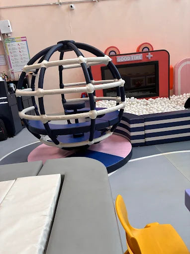 A colorful indoor playground with a ball pit and a spinning globe structure for young children.