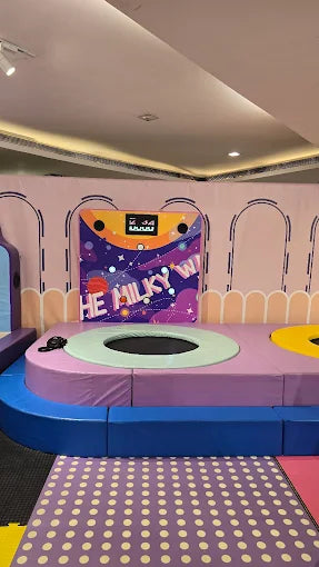 A colorful indoor playground with trampolines and soft play areas for children.