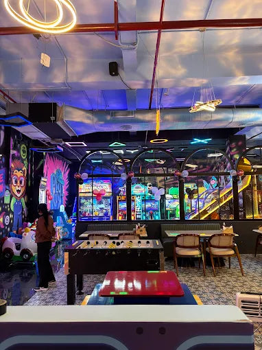 A lively arcade with foosball tables, arcade games, and people enjoying the entertainment.