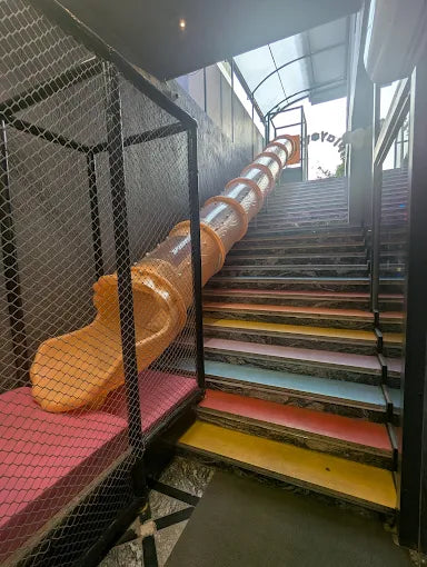 A colorful playground slide descends next to a staircase.