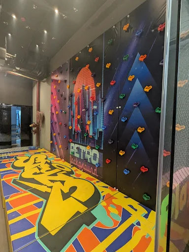 A climbing wall with a retro city background and colorful graffiti matting.