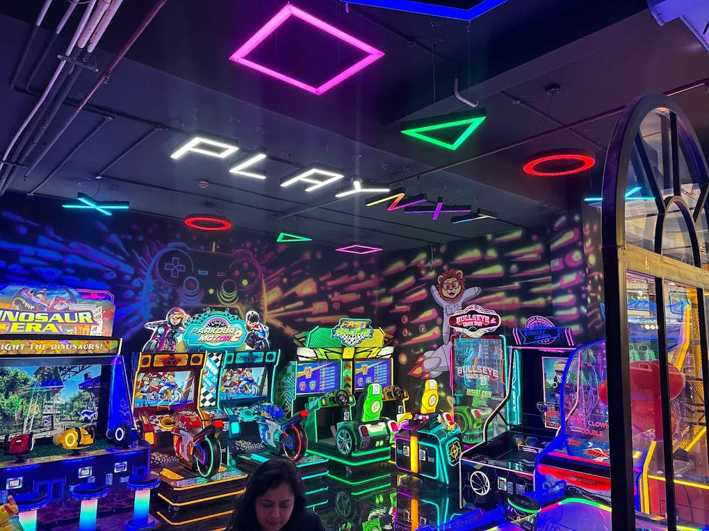 An arcade with neon lights and various games, including motorcycle racing and shooting games.