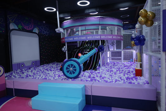 A colorful indoor playground with a ball pit, slide, and play structures for children.