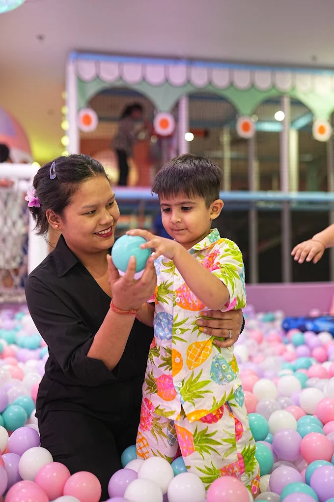 A woman and a young boy play with a ball in a ball pit.