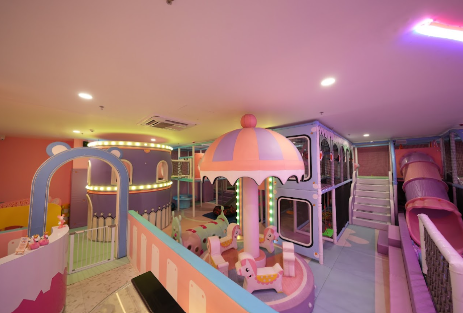 A colorful indoor playground for children with slides, a carousel, and climbing structures.