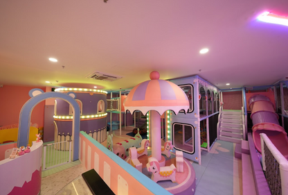 A colorful indoor playground for children with slides, a carousel, and climbing structures.