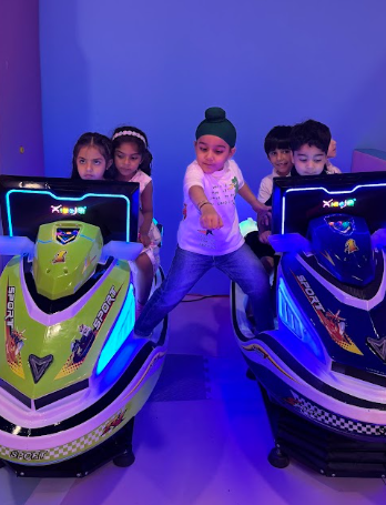 Children playing on arcade racing simulators in a brightly lit room.