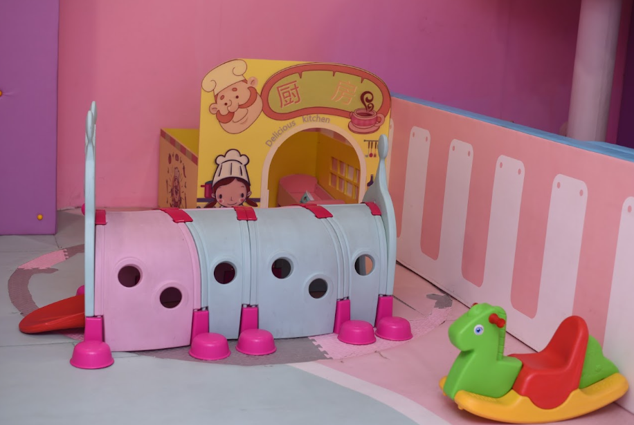 A colorful indoor play area with a tunnel and a rocking horse for young children.