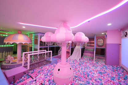 A brightly lit indoor playground filled with colorful balls, slides, and soft play structures for children.