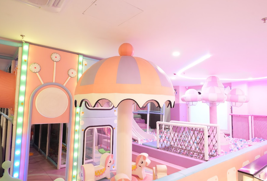 A colorful indoor playground with slides, ball pits, and unicorn-themed rides for children.