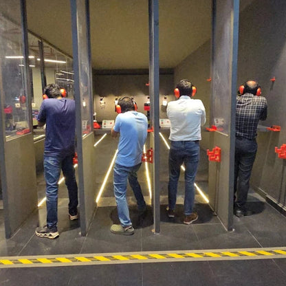 Men in a shooting range, wearing ear protection and aiming at targets.