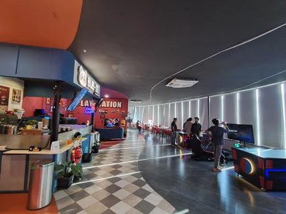 Young adults play racing simulation games in a brightly lit entertainment center.