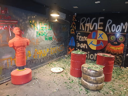 A rage room with a punching dummy, graffiti, and broken glass.