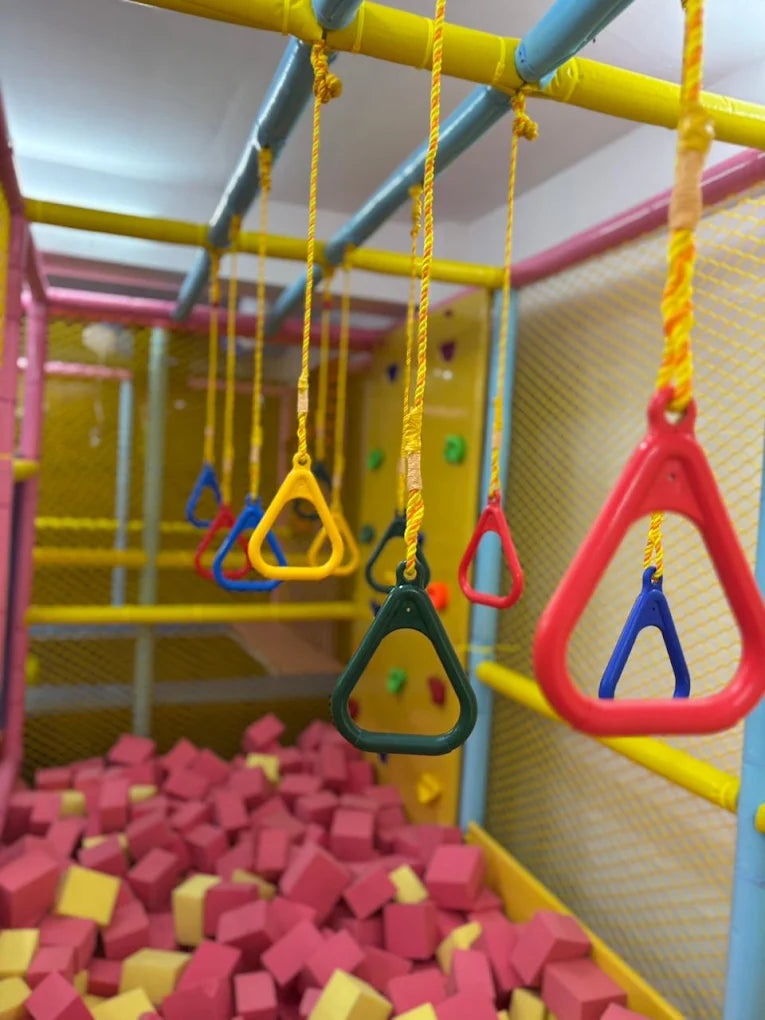 Children's indoor playground with colorful rings hanging over a foam pit.