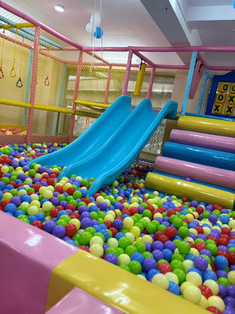 A colorful ball pit with blue slides in a children's play area.