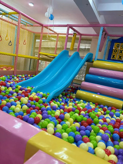 A colorful ball pit with blue slides in a children's play area.