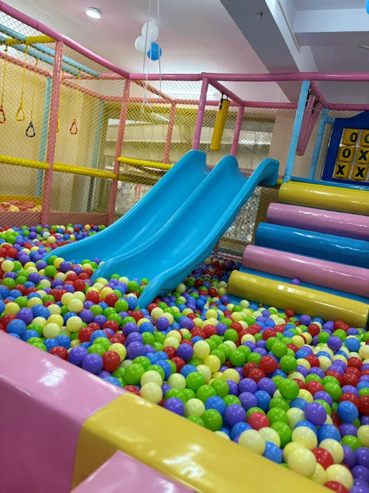 A colorful ball pit with blue slides in a children's play area.