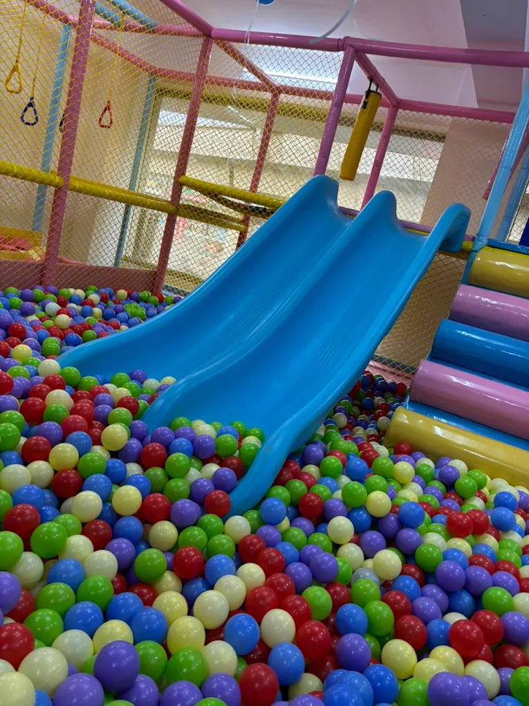 A colorful ball pit with blue slides in a children's play area.