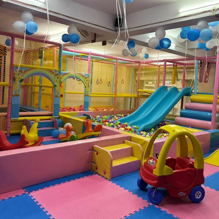 A colorful indoor playground with slides, ball pit, and ride-on toys for young children.