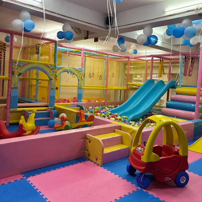 A colorful indoor playground with slides, ball pit, and ride-on toys for young children.
