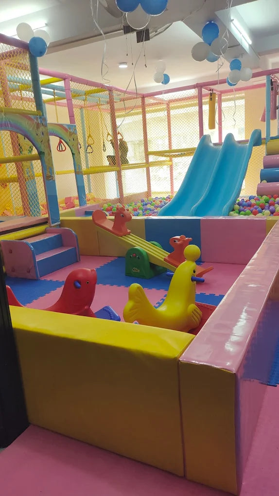 A colorful indoor playground with slides, ball pits, and soft play structures for young children.
