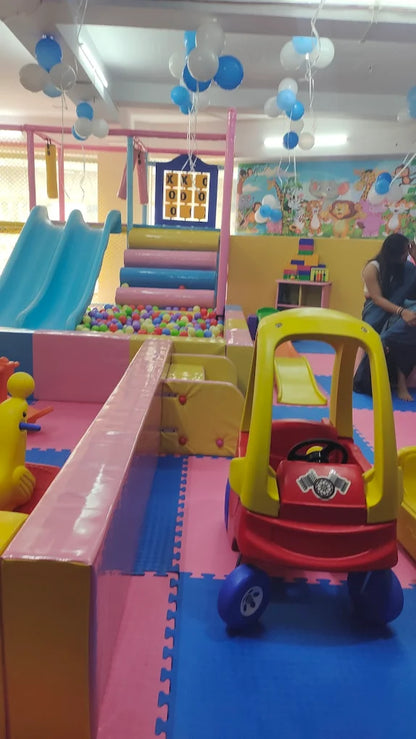 A colorful indoor playground with a ball pit, slides, and a toy car, likely for young children.