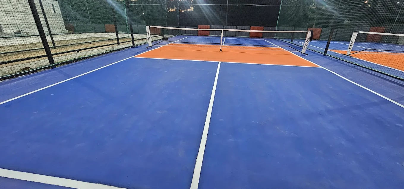 A blue and orange tennis court with nets and white lines.