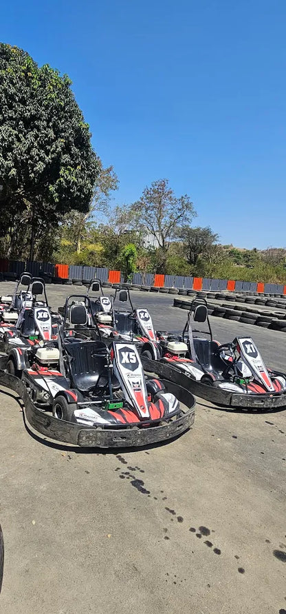 Go-karts lined up on a track under a clear blue sky, ready for racing.