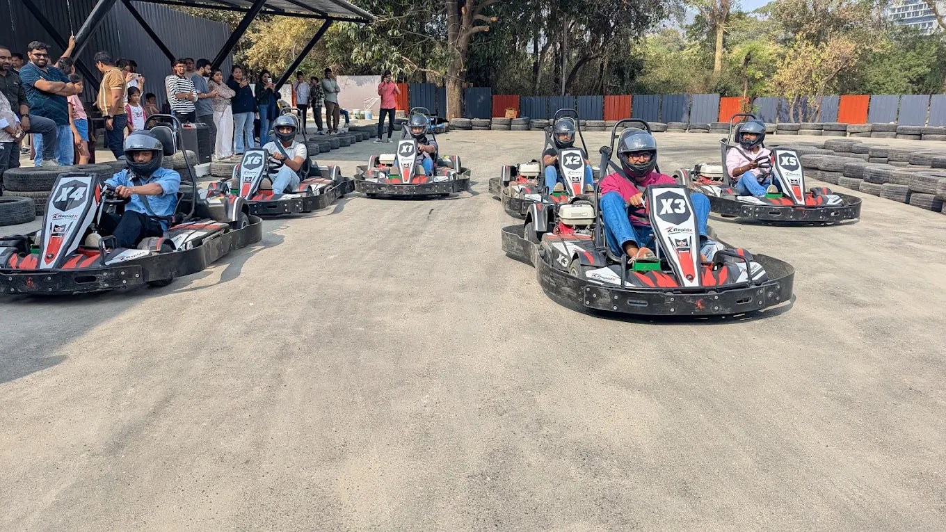 Adults in go-karts on a track, with spectators in the background.