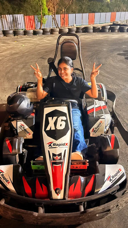 A young woman in a go-kart smiles and makes a peace sign.