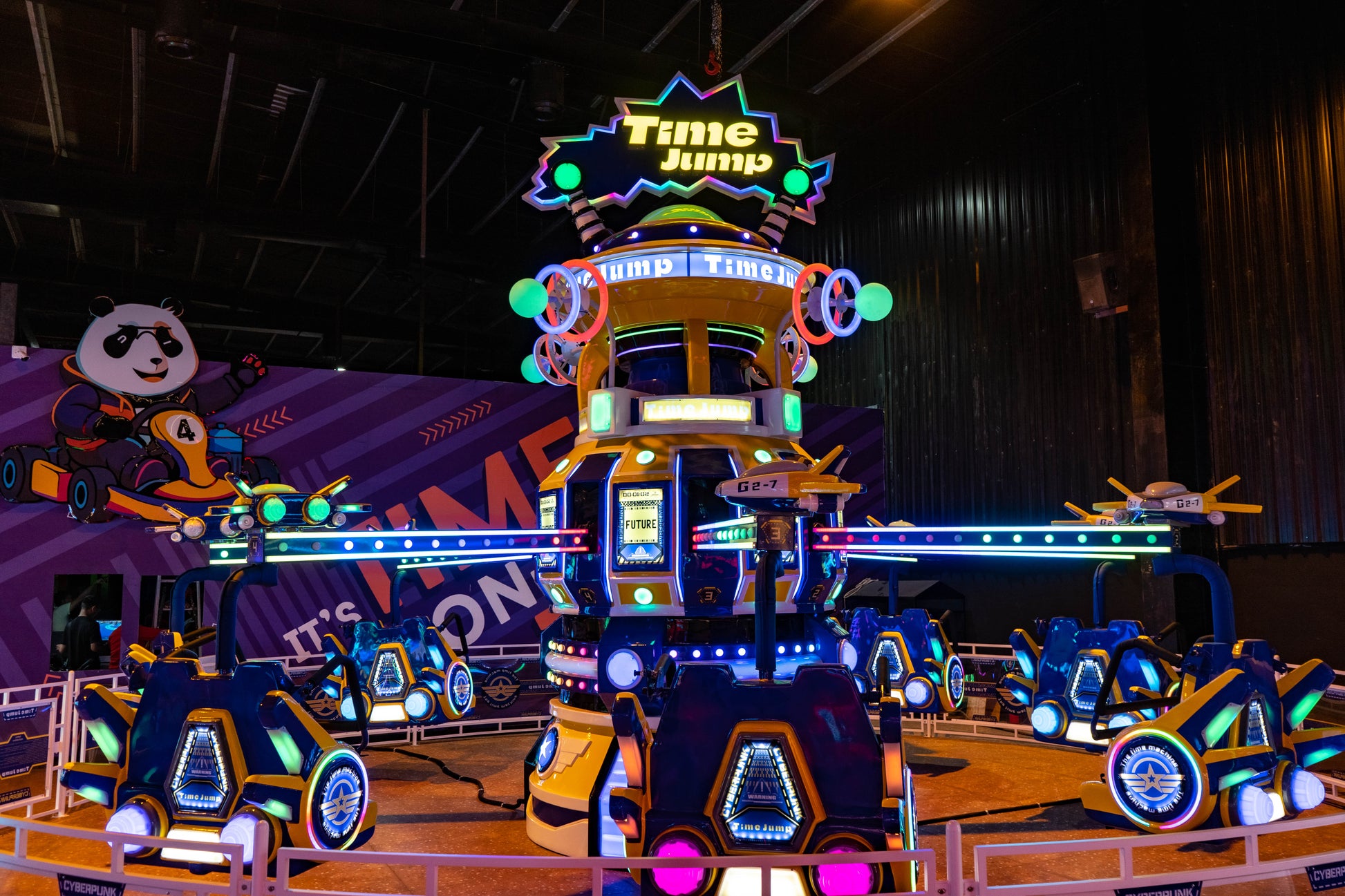 A neon-lit amusement park ride with futuristic pods and a panda mascot.