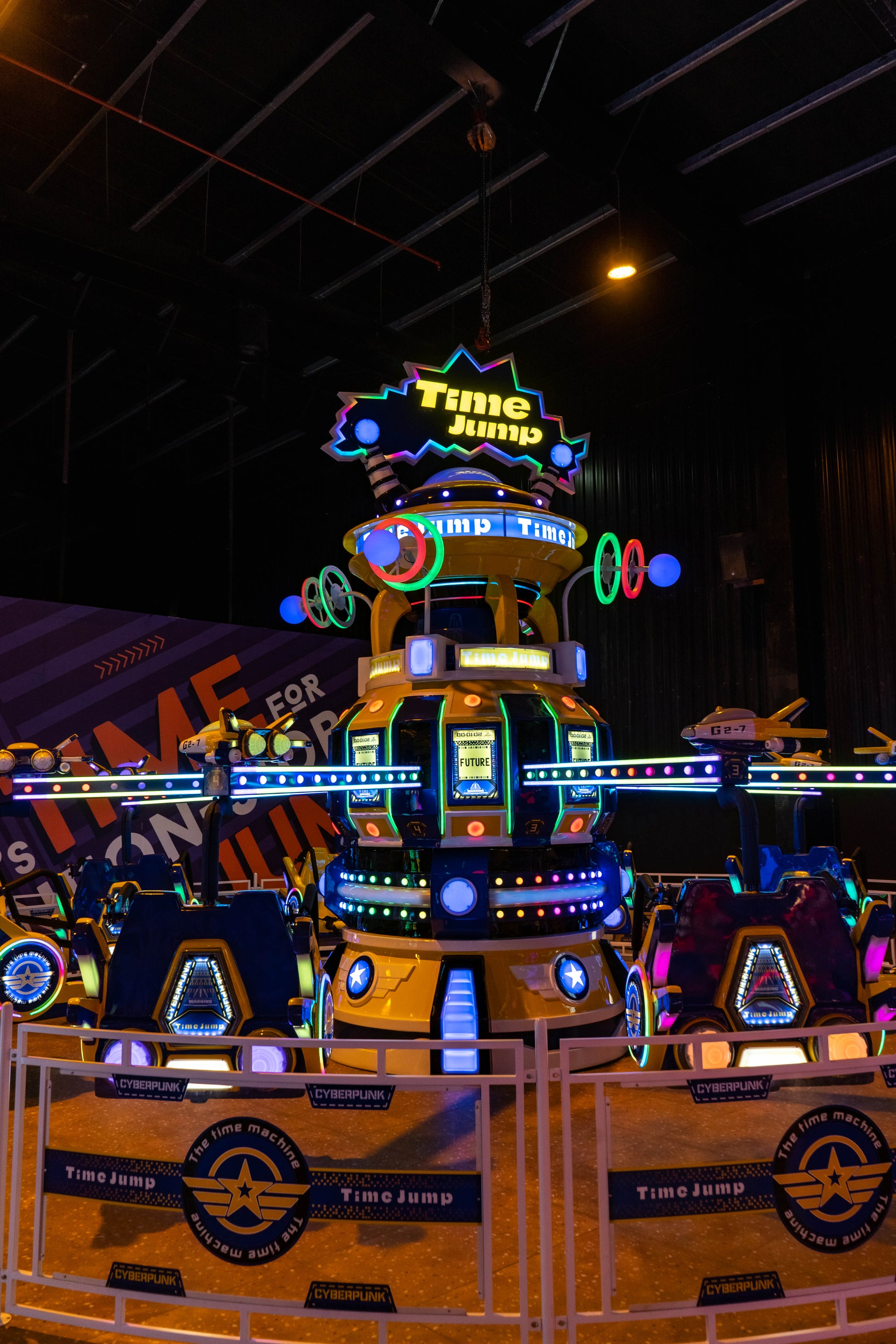 A brightly lit "Time Jump" amusement ride with futuristic vehicles and neon lights in an indoor arcade.