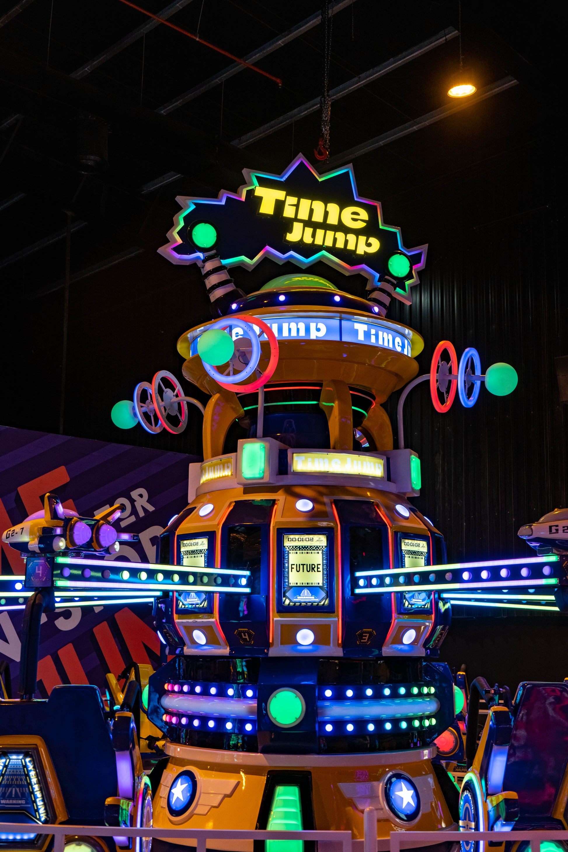 A brightly lit amusement ride with a "Time Jump" sign, featuring futuristic pods and neon lights.