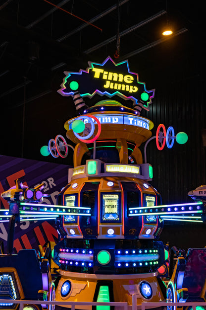 A brightly lit amusement ride with a "Time Jump" sign, featuring futuristic pods and neon lights.