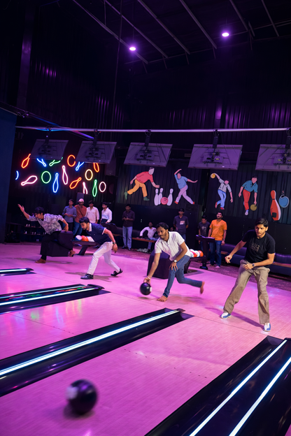 Young men bowling in a neon-lit alley.
