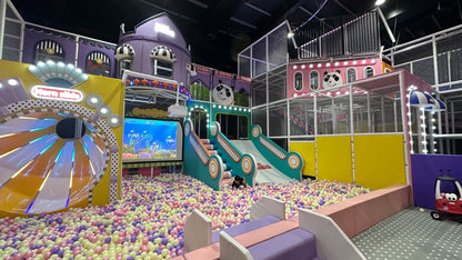 A colorful indoor playground with slides, ball pit, and interactive screen, where children play.