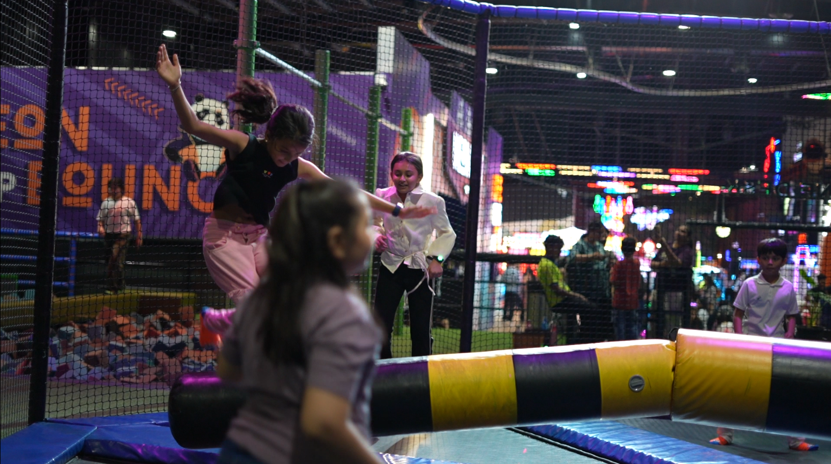 Children jump on trampolines in a brightly lit indoor play area.