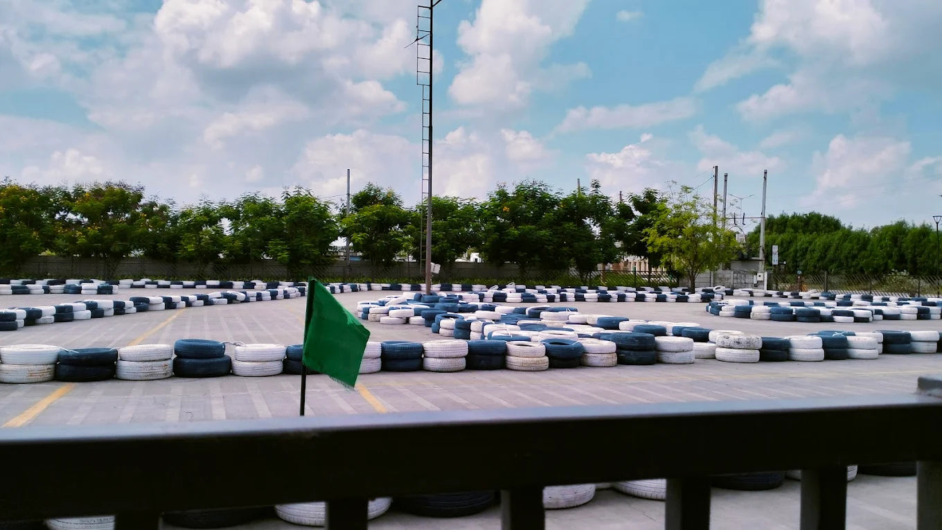 A go-kart track with tire barriers under a cloudy sky.