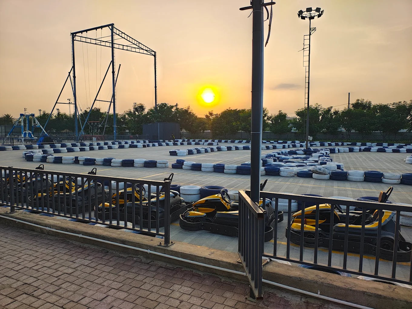 Go-karts lined up at a track during sunset, with a bungee jump structure in the background.