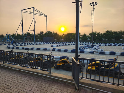 Go-karts lined up at a track during sunset, with a bungee jump structure in the background.