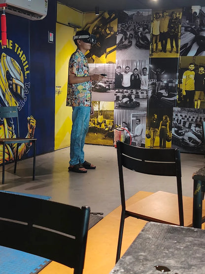 A young person plays a VR game in a go-kart themed arcade.