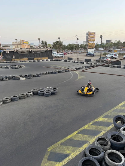A person races a go-kart on a track lined with tires.