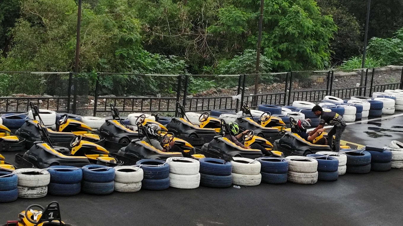 Go-karts lined up with people preparing to race, with a person assisting a driver.