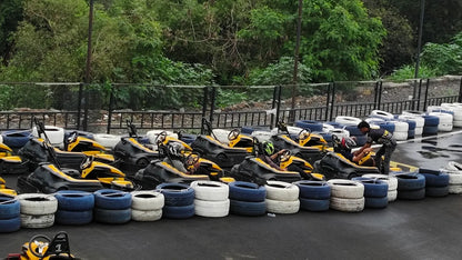 Go-karts lined up with people preparing to race, with a person assisting a driver.