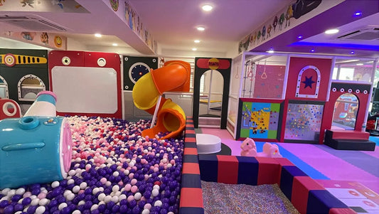 A colorful indoor playground with a ball pit, slides, and climbing structures for children.