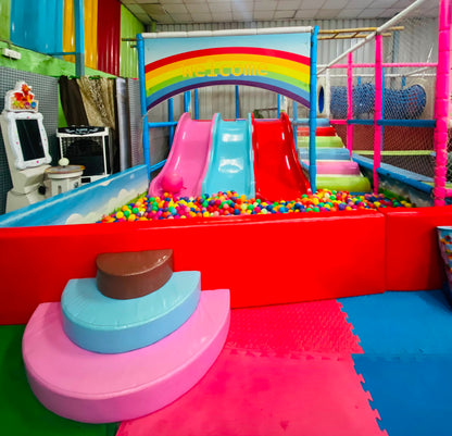 A colorful indoor playground with slides, a ball pit, and soft play structures for children.