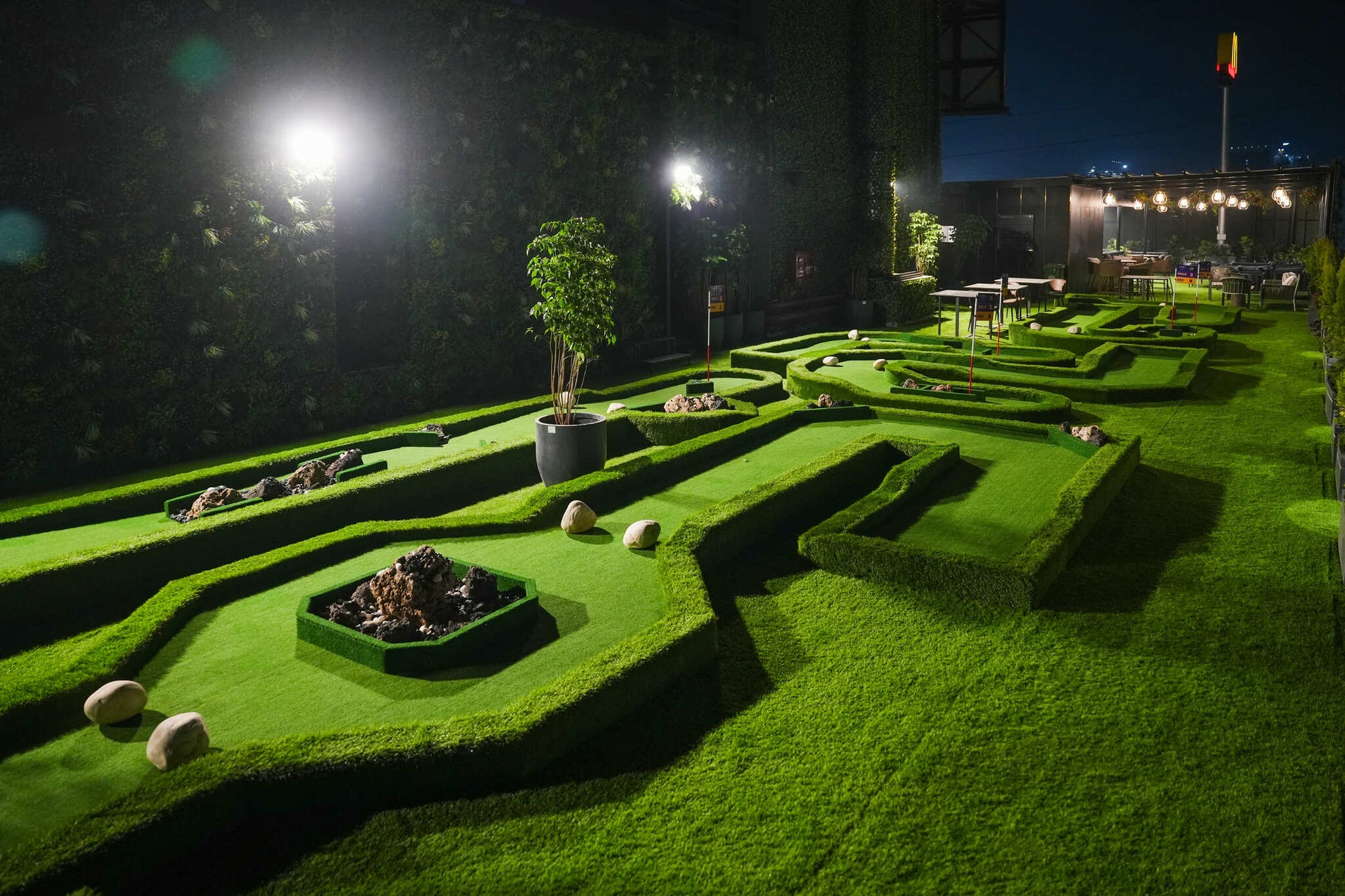 Outdoor mini golf course with sculpted greenery and ambient lighting at Rumble Zone Sector 57 Gurugram
