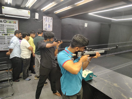 Adults practice shooting at a rifle range, with one person aiming a rifle.