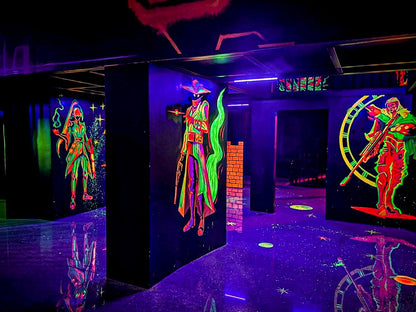 Neon characters on black walls in a dark laser tag arena.