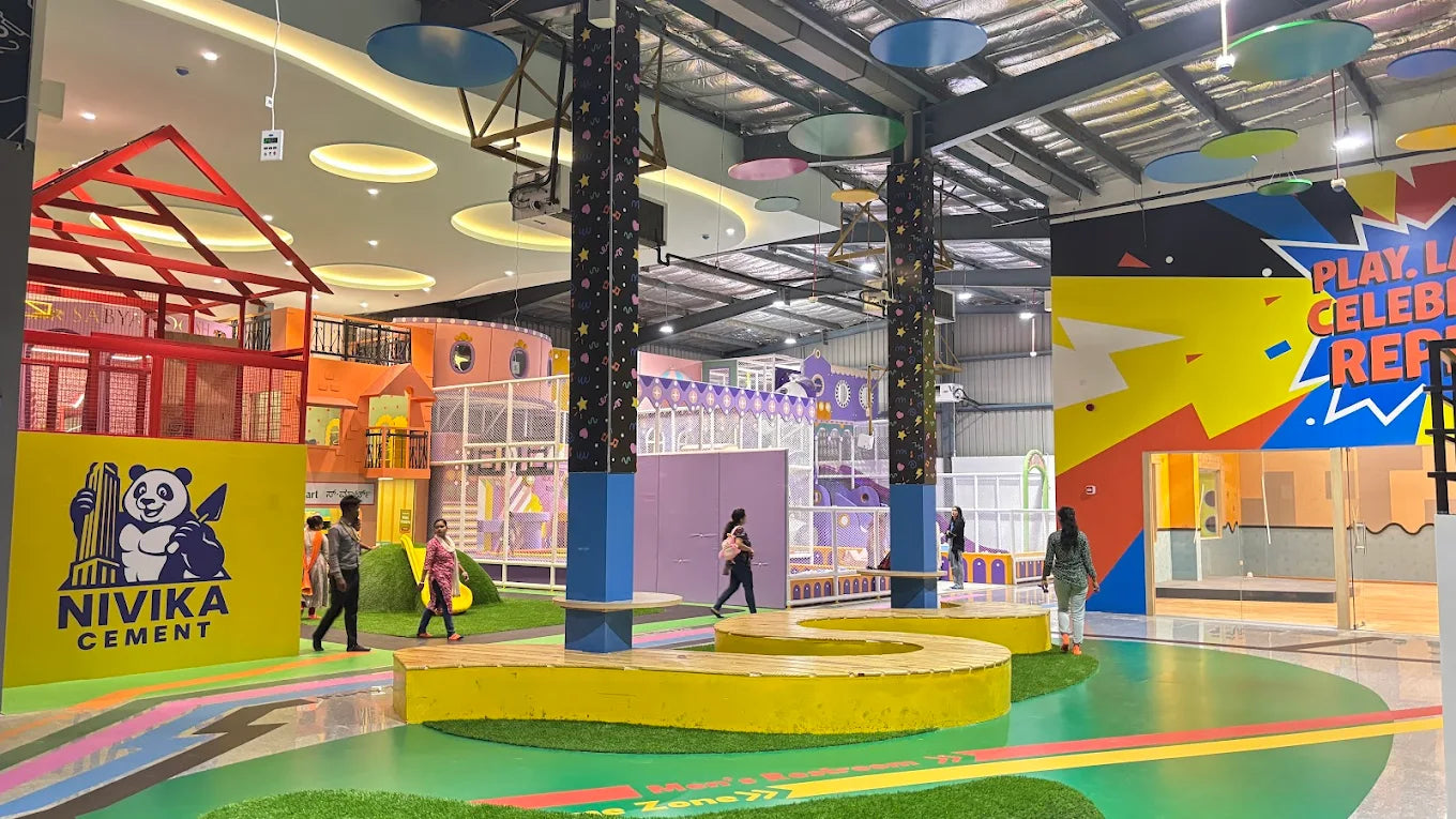 A colorful indoor playground with children playing and adults supervising.